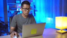freelance man working on laptop At home at night. Man freelancing, thinking, serious while working at home at night. Freelance work and work from home concept.