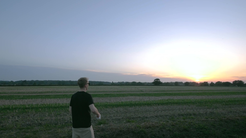 Man has a drink looking admiring sunset