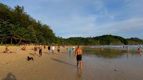 Phuket, Thailand, 10, March, 2022:
A lot of people walk along the tropical beach in the evening, crowds of people on the beaches of Phuket in the evening