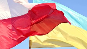 Developing waving  Ukrainian and Polish flags on a blue peaceful sky, support for friendly countries  war in Ukraine - Powered by Shutterstock - Get 15% off with code: PIKWIZARD15