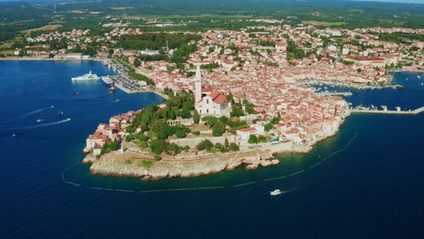 Rovinj city and surroundings on Istria peninsula washed by water of Adriatic sea. Church of St. Euphemia and houses with red roofs in coastal town. Aerial view