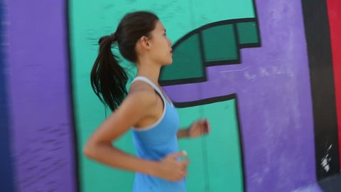 Running woman jogging by Berlin Wall, Germany. Female runner training outdoors in city for marathon. Mixed race Asian Caucasian female model.
