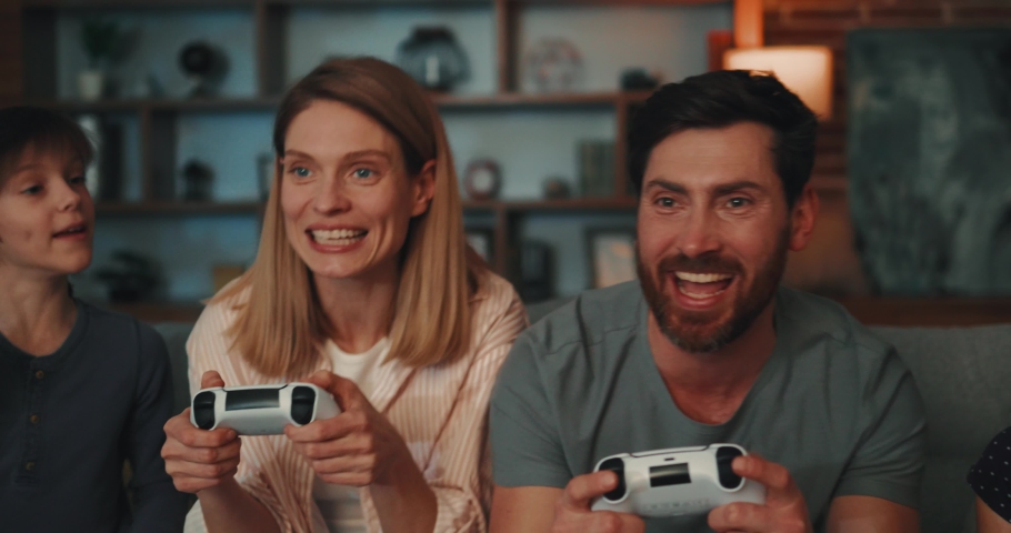 Married Couple Playing Video Games.  Mother and Father uses PlayStation holding Joystick Spending Time with Son and Daughter at home Royalty-Free Stock Footage #1088386569