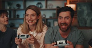 Married Couple Playing Video Games.  Mother and Father uses PlayStation holding Joystick Spending Time with Son and Daughter at home