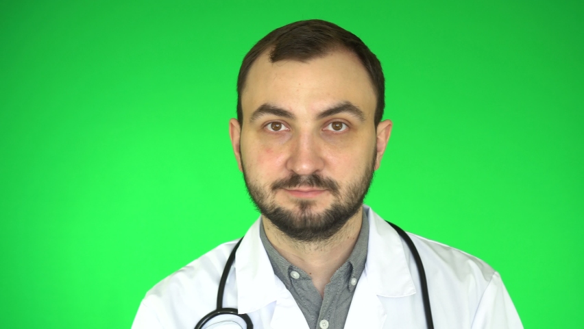 Medical doctor man winking and smiling at camera. Green screen background, chroma key.