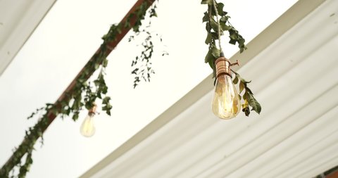 Hanging light bulb Wedding  decoration under tree in nights. Decorative lamps for events, dinners, nights, parties. String lights under white theme wedding tent. Close-up shots. 