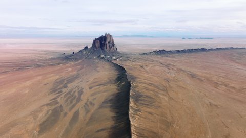 Drone footage of beautiful natural environment with dry climate. Rocky range of Shiprock, covered with yellow soil and sand as seen from above. High quality 4k footage