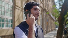 A young Indian Asian hipster modern stylish male or man is standing outdoors against an old vintage urban building and talking or having a conversation on a Mobile phone or smartphone in daylight.  - Powered by Shutterstock - Get 15% off with code: PIKWIZARD15