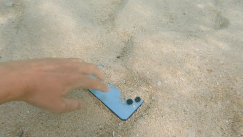 Pov footage of beautiful underwater sea bottom with white sand swirling with stream and cellphone with blue screen for chroma key being taken by anonymous man. Waterproof handphone.
