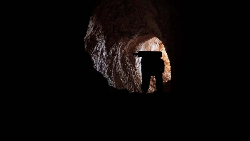 Traveler descends with rope into cave. Person exploring cave tunnel going down. Man descending extremely on rope into dark cave tunnel Royalty-Free Stock Footage #1088394185
