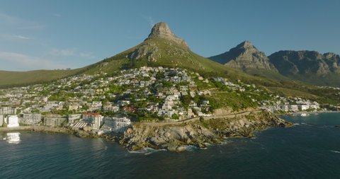 Forwards fly above sea coast. Luxury residences and apartments on sunny slope under Lions Head mountain. Cape Town, South Africa