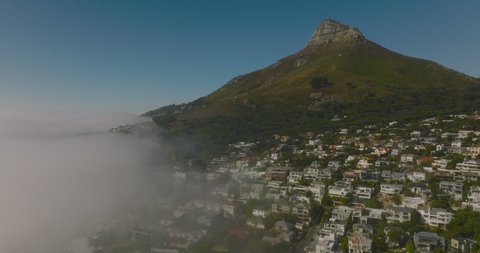Aerial view of Camps Bay luxurious residential suburb and steep slope with rocky peak above. Cape Town, South Africa