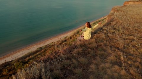 Happy carefree woman with dog sitting on cliff and enjoying amazing view above sea water. Local summer traveling to the Black Sea. Yuzhne Odessa region, Ukraine
