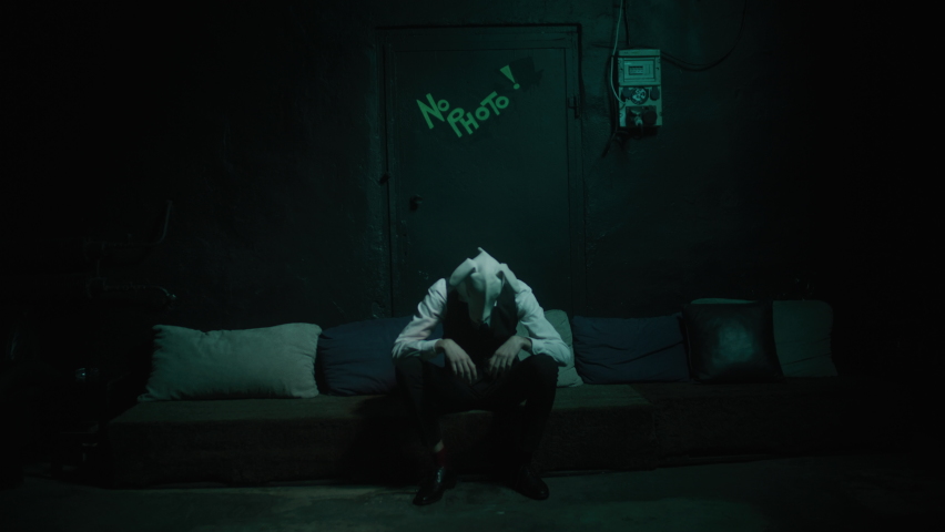 Anxiety and depression concept. Sad, lonely man in mask sitting alone in a dark room. Scary, creepy vision, drug addiction and abuse. Night scene, dirty, grungy club, isolated man in a rabbit mask. Royalty-Free Stock Footage #1088397581