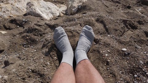 Male feet in socks. The point of view of a man who sits on the beach in socks.