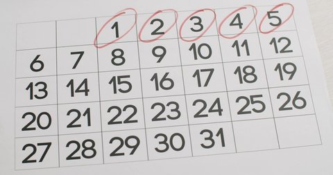 Man's hand Write down the 6,7,8,9,10,11,12th day on the paper calendar using a red pen. Very important date in the calendar. Signing a day on a calendar. Calendar date of the month cut.