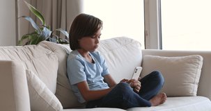 Bad habit, modern tech overuse, user of social media concept. Pre-teen boy sit on sofa holding smartphone, watch vlog, listen favourite music video online, spend leisure absorbed in technology usage