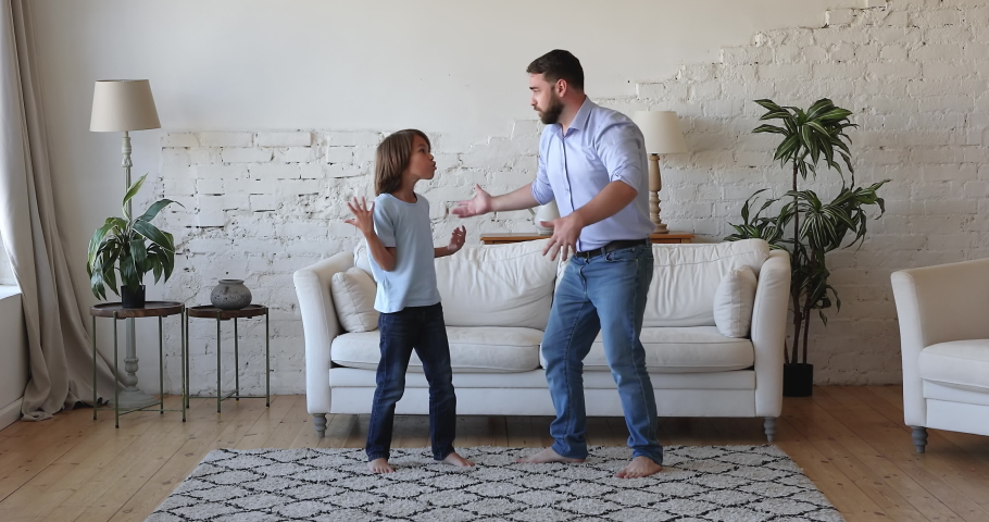 Young dad and son dance at home, sing favourite song, moving barefoot on carpet have fun in modern living room. Family weekend leisure activity, festive mood, happy homeowners enjoy holidays concept Royalty-Free Stock Footage #1088401093