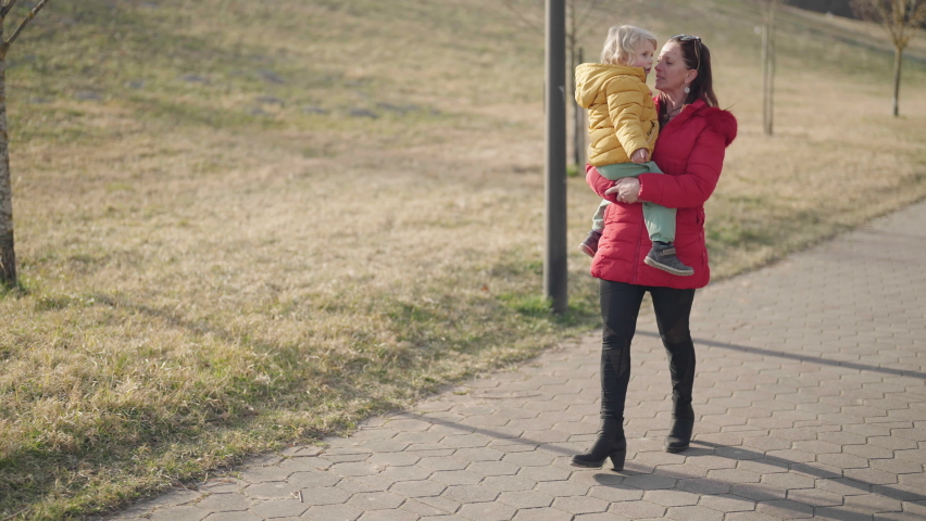 Youthful grandmother carry grandchild while walking in park 4K