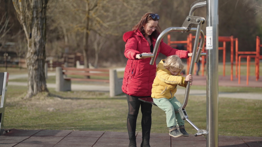 Grandmother playing with grandson on outdoor gym equipment 4K