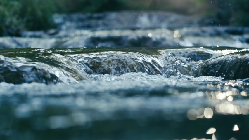 Clear stream running through stone boulders Abundant river flowing on stone bottom in slow motion. Wild mountain river water splashing in summer day.underwater bubbles. split view.. 4K. Royalty-Free Stock Footage #1088404309