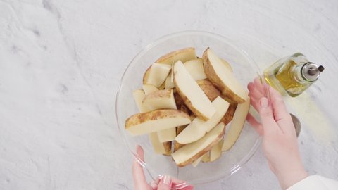 Flat lay. Step by step. Soaking potato wedges in a bowl of water to prepare baked potato wedges with spices.