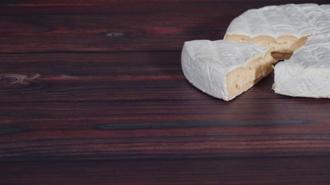 Large wedge of triple cream brie cheese on a rustic wood background.