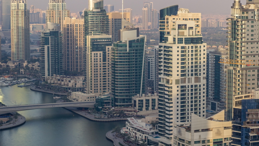 Amazing colorful dubai marina skyline with bridges during sunset timelapse. Great perspective of multiple tallest skyscrapers with yachts and boats. Sunlight over buildings. United Arab Emirates.