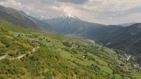 Aerial drone view of the majestic Caucasus mountains landscape in Svaneti region, Georgia. Two unidentified tourists with backpacks hiking the Mestia to Ushguli village trek