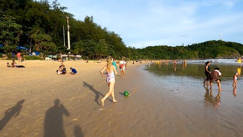 Phuket, Thailand, 10, March, 2022:
Mom plays ball with her son on the beach, mom kicks the ball to her son in the evening on the beach