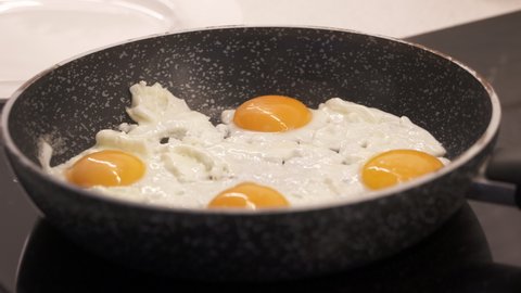 Cooking scrambled eggs on skillet. Woman stirring eggs on skillet to prepare scrambled eggs for breakfast. Cooking process. High quality 4k footage