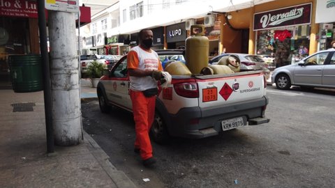Teresopolis, RJ, Brazil - March 18th 2022 - Gas and water deliveryman. Man delivering gas canisters, and water gallons with a truck. City, urban, street.