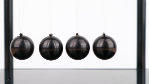 Macro shot, Newton's Cradle metal balls on wooden desk, swinging metal balls, Close up.