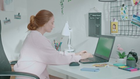 Female designer using laptop at home and answer phone