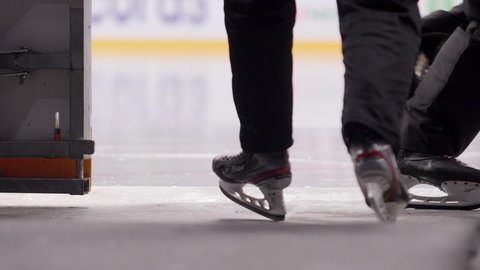 Professional hockey judges skate on ice rink during match at stadium closeup slow motion. Winter sports competition