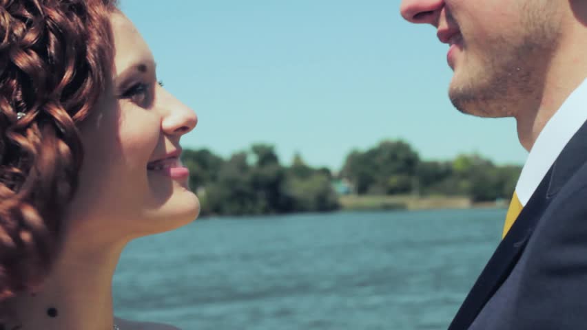 Newlyweds kissing on the background of a lake on a hot , sunny day . Wedding.