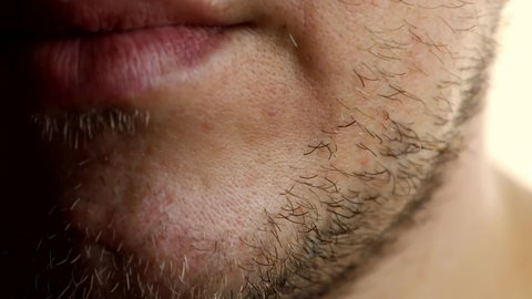 An unshaven guy checks his stubble with his hand before shaving.