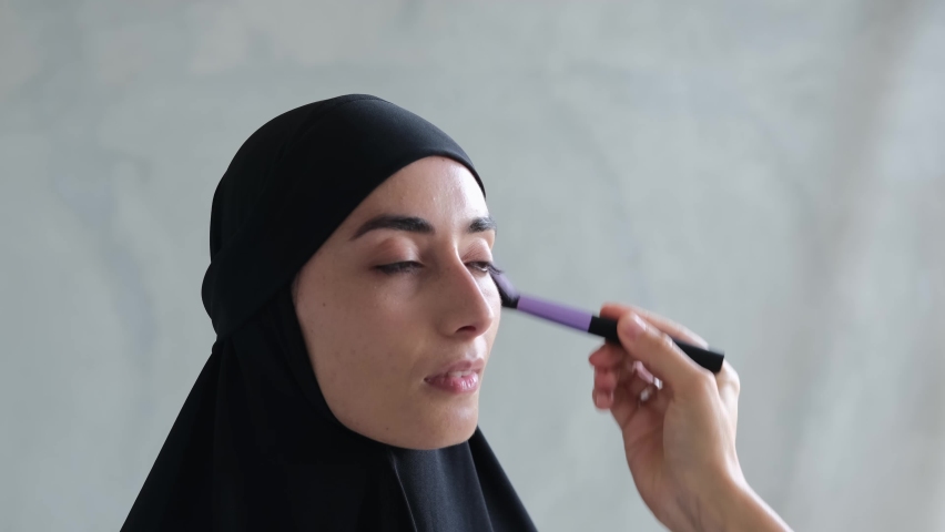 A Muslim woman TV presenter is preparing to speak in a media program, a stylist helps her put on a make-up before the broadcast. The newest Islamic world with changes in women's freedoms. | Shutterstock HD Video #1088417723