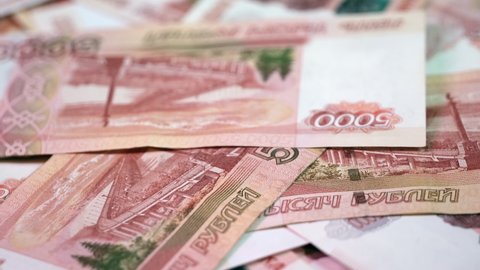 A bundle of paper money 5000 Russian banknotes lies on a clockwise rotating platform. Background Covered with banknotes of five thousand rubles. Close-up