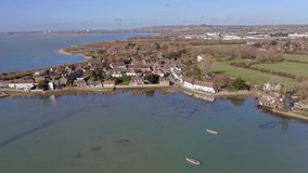 Aerial footage over Langstone Harbour towards a row of traditional English cottages in an area to the south of Havant on the waterfront of the harbour.