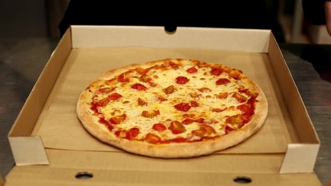 Pizzaiolo cuts a hot fragrant margherita pizza. Pizzeria, pizza delivery.