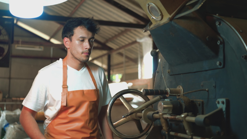 Men smell coffee beans and check the quality from roasting machines. Young Man half-Asian-caucasian 29 years old working in a coffee factory. Small business owner, coffee roaster Royalty-Free Stock Footage #1088422617