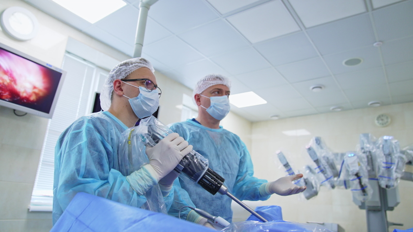 Focused surgeons look in front of them on the screen. Surgery specialists use robotic equipment and newest devices at operation. | Shutterstock HD Video #1088424725