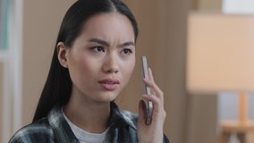Portrait asian woman millennial confused angry girl indoors talking on phone answering call worries about bad mobile connection network problems cellular trouble broken smartphone breaking telephone - Powered by Shutterstock - Get 15% off with code: PIKWIZARD15