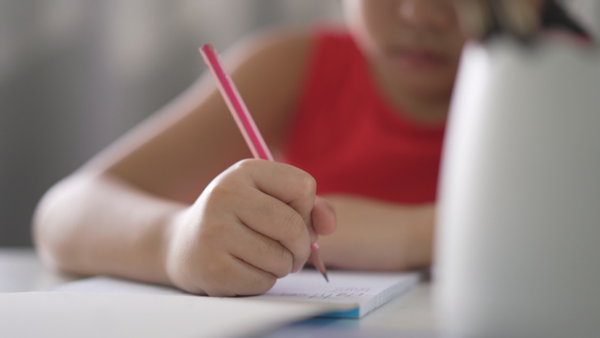 closeup hand of asian child write learning or kid girl student doing homework on book to learn from homeschool and person training writing on paper and desk by back to school to study online class Royalty-Free Stock Footage #1088430753