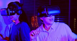 Asian couples wearing modern Virtual reality glasses sit and watch movies in living room at home. Holiday Activity family entertainment technology. living together happiness. Concept meta verse