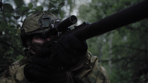 Close-up, an armed soldier with a sniper rifle, in a dense forest, completed a special operation. Equipped soldier in action