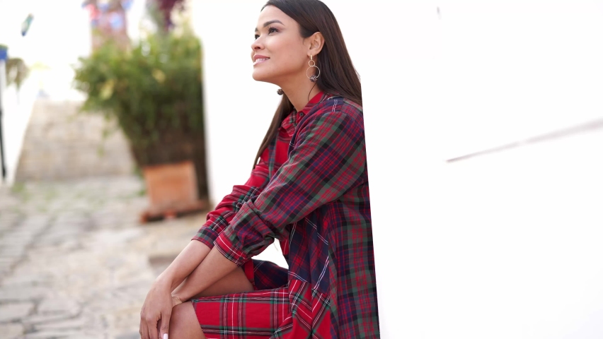 Smiling ethnic woman sitting on street