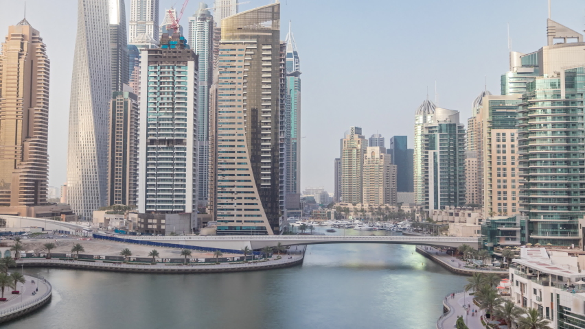 Amazing towers of dubai marina skyline during sunset timelapse. Great perspective of multiple tallest skyscrapers with yachts and boats. Sunlight over buildings. United Arab Emirates.