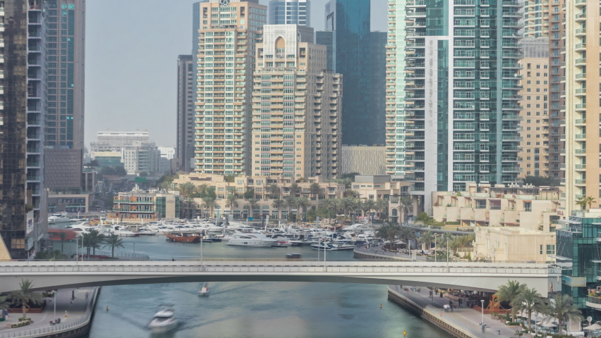 Amazing colorful dubai marina skyline during sunset timelapse. Great perspective of multiple tallest skyscrapers and bridge with yachts and boats. Sunlight over buildings. United Arab Emirates.